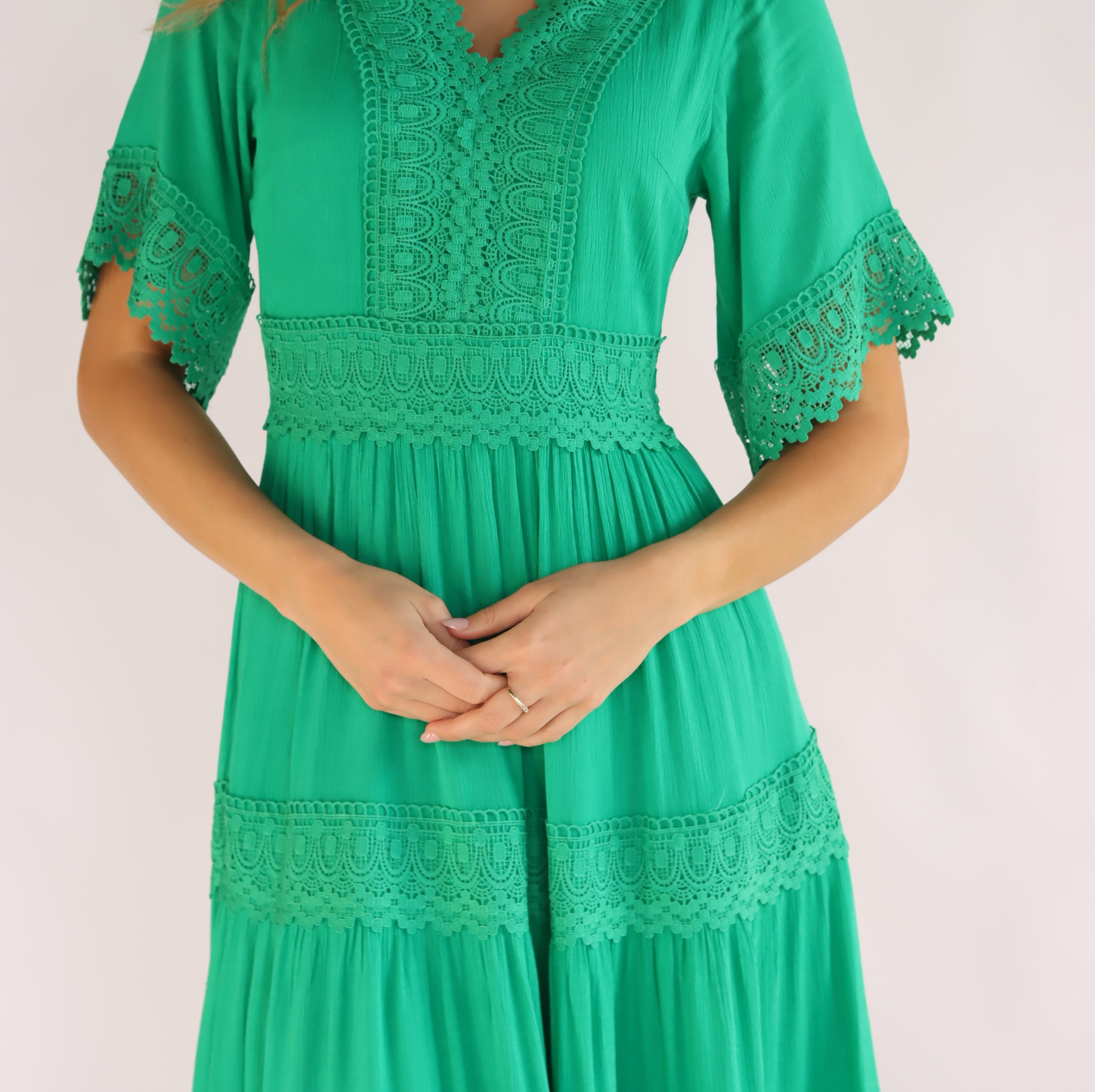 Woman wearing a green dress with lace details on a white background