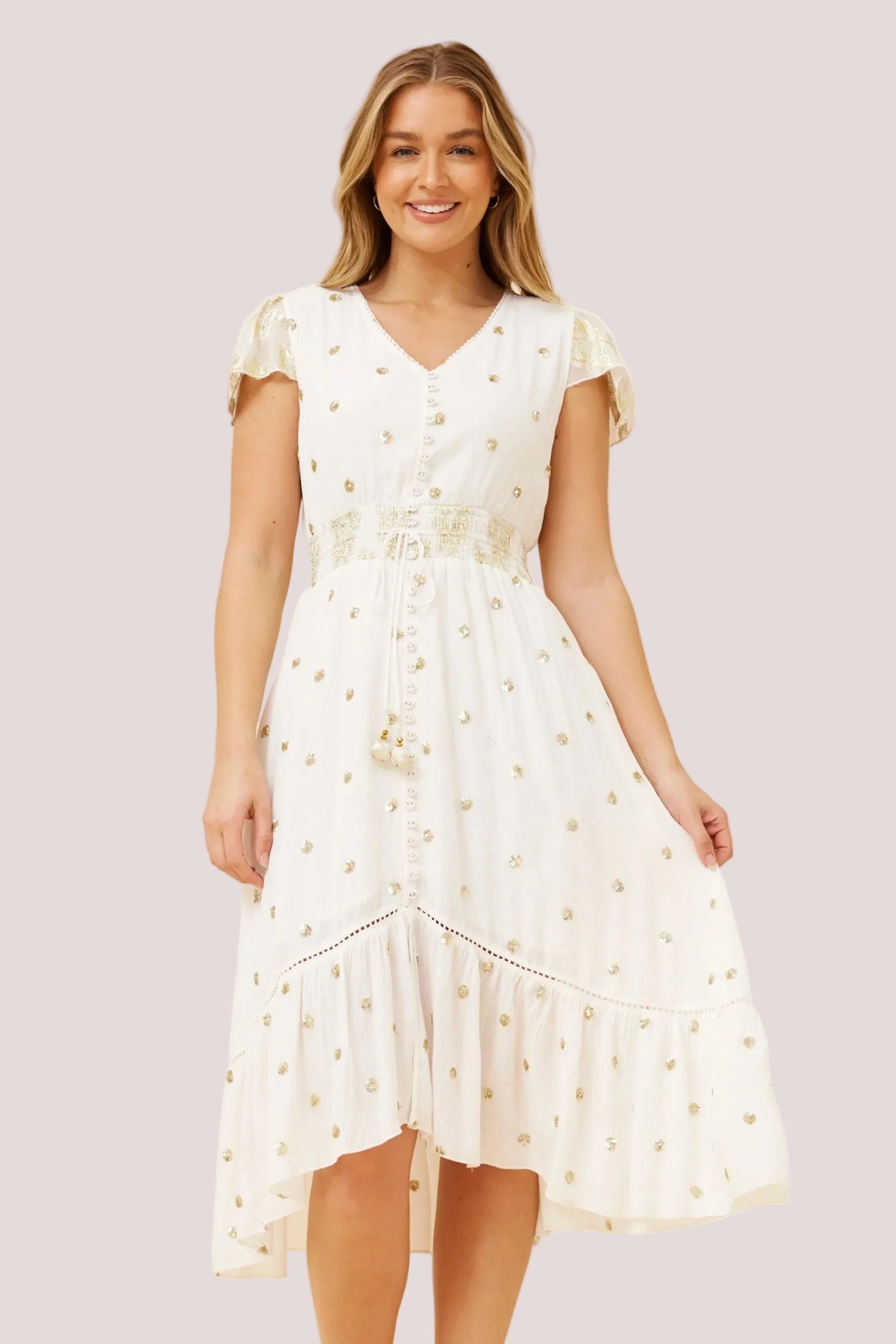 Woman wearing a white dress with gold accents on a beige background