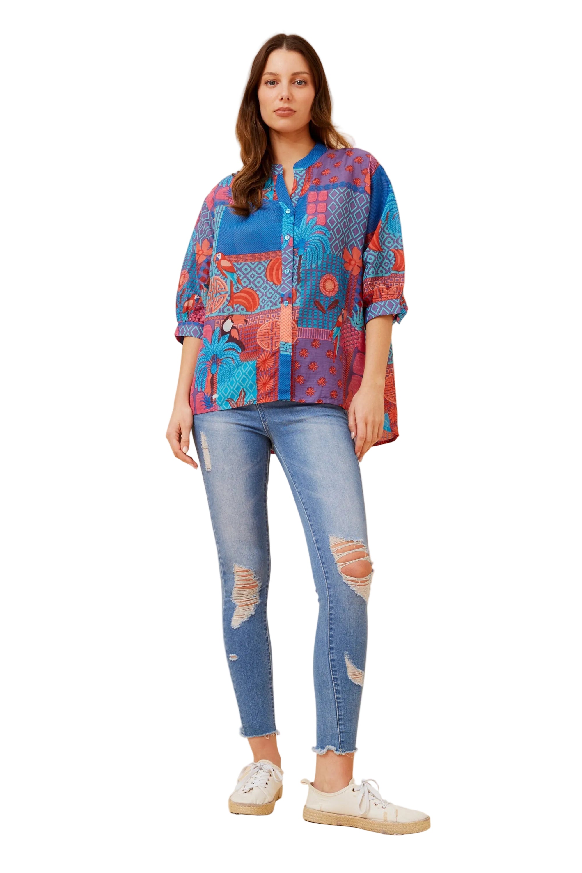 Woman wearing a colorful patterned shirt and blue jeans on a white background