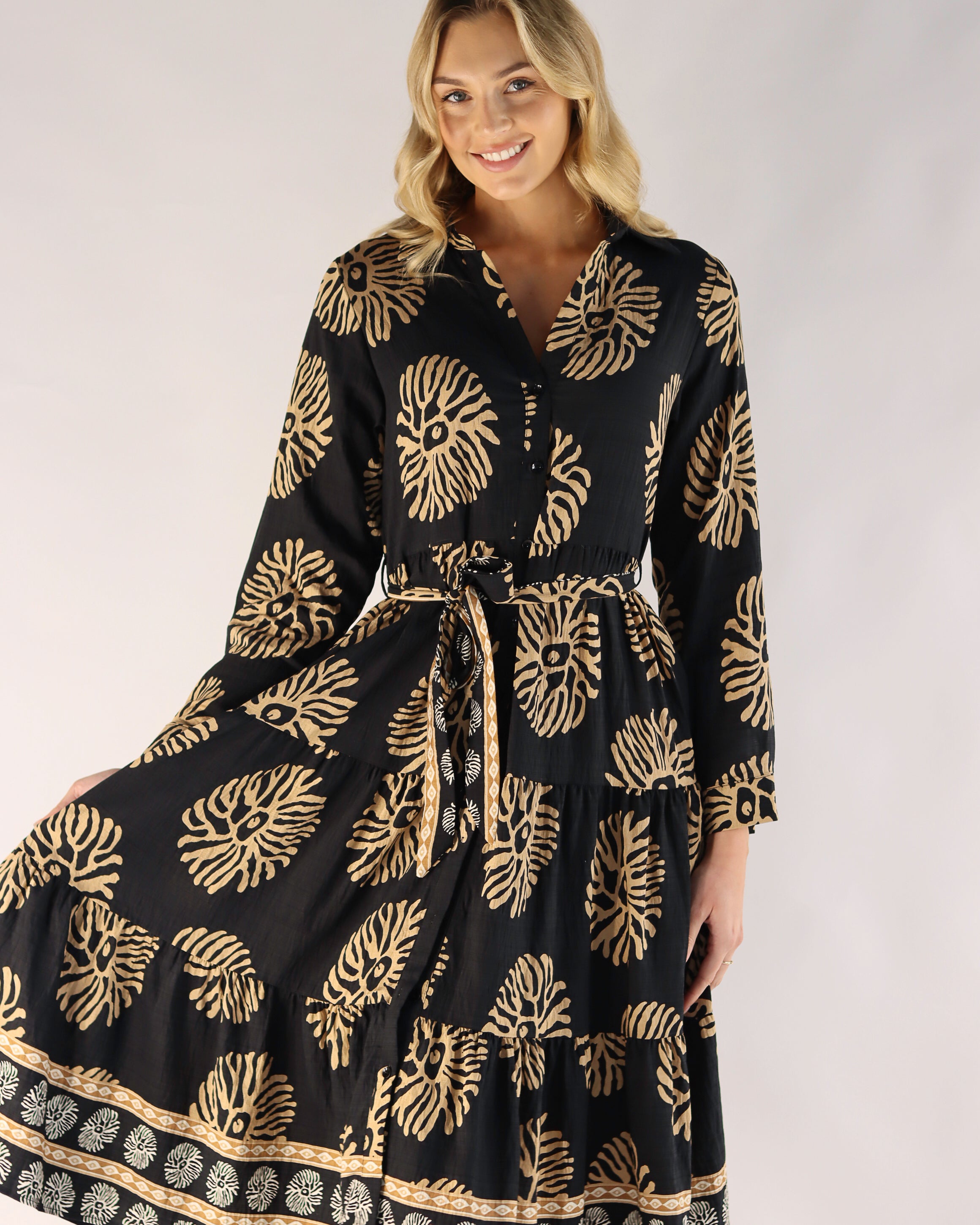 Woman wearing a black dress with gold patterns on a white background