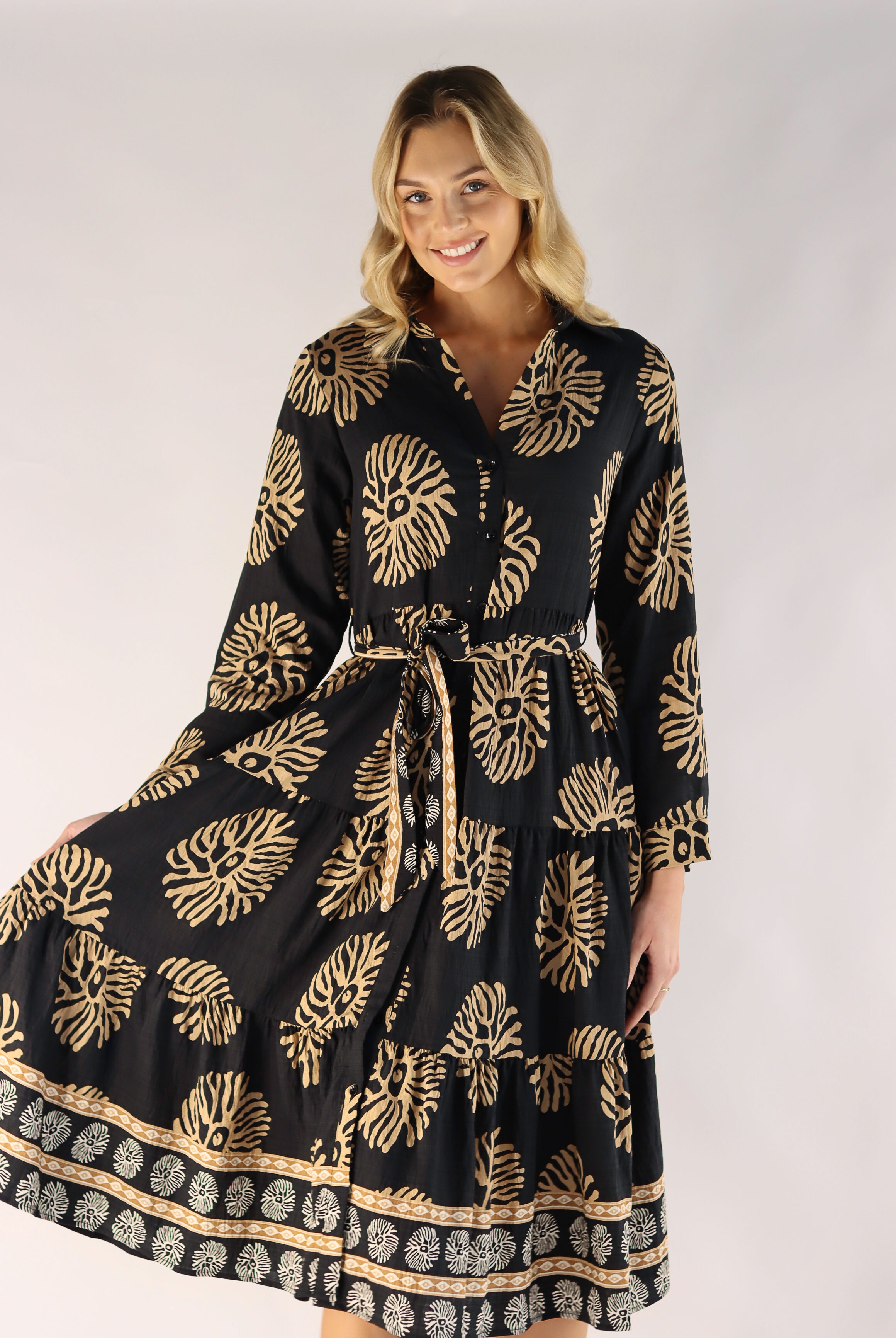 Woman wearing a black dress with gold patterns on a white background