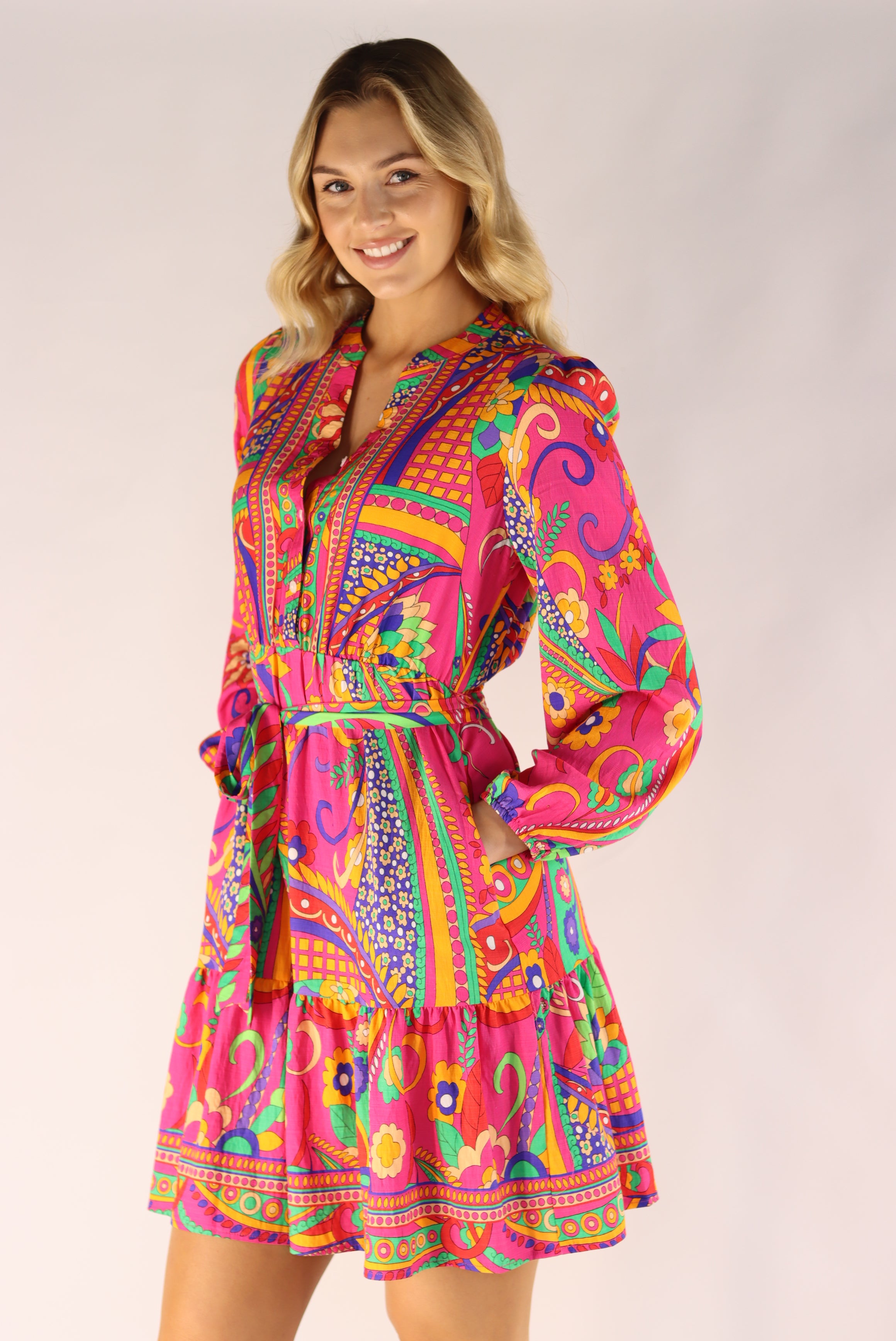 Woman wearing a colorful patterned dress on a plain background
