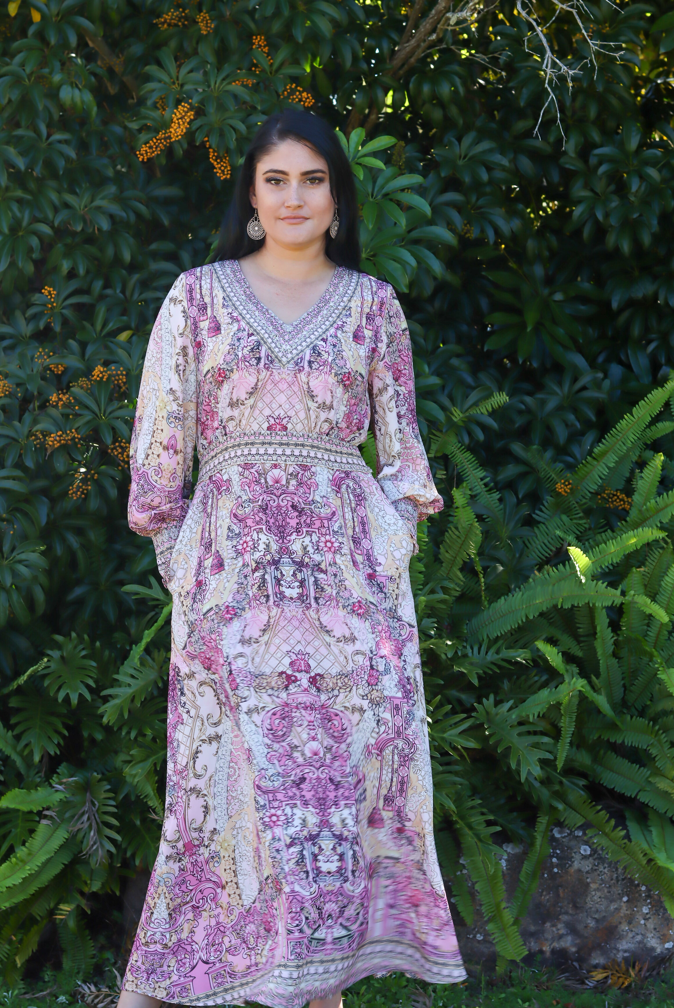 Woman wearing a floral dress standing in front of green foliage