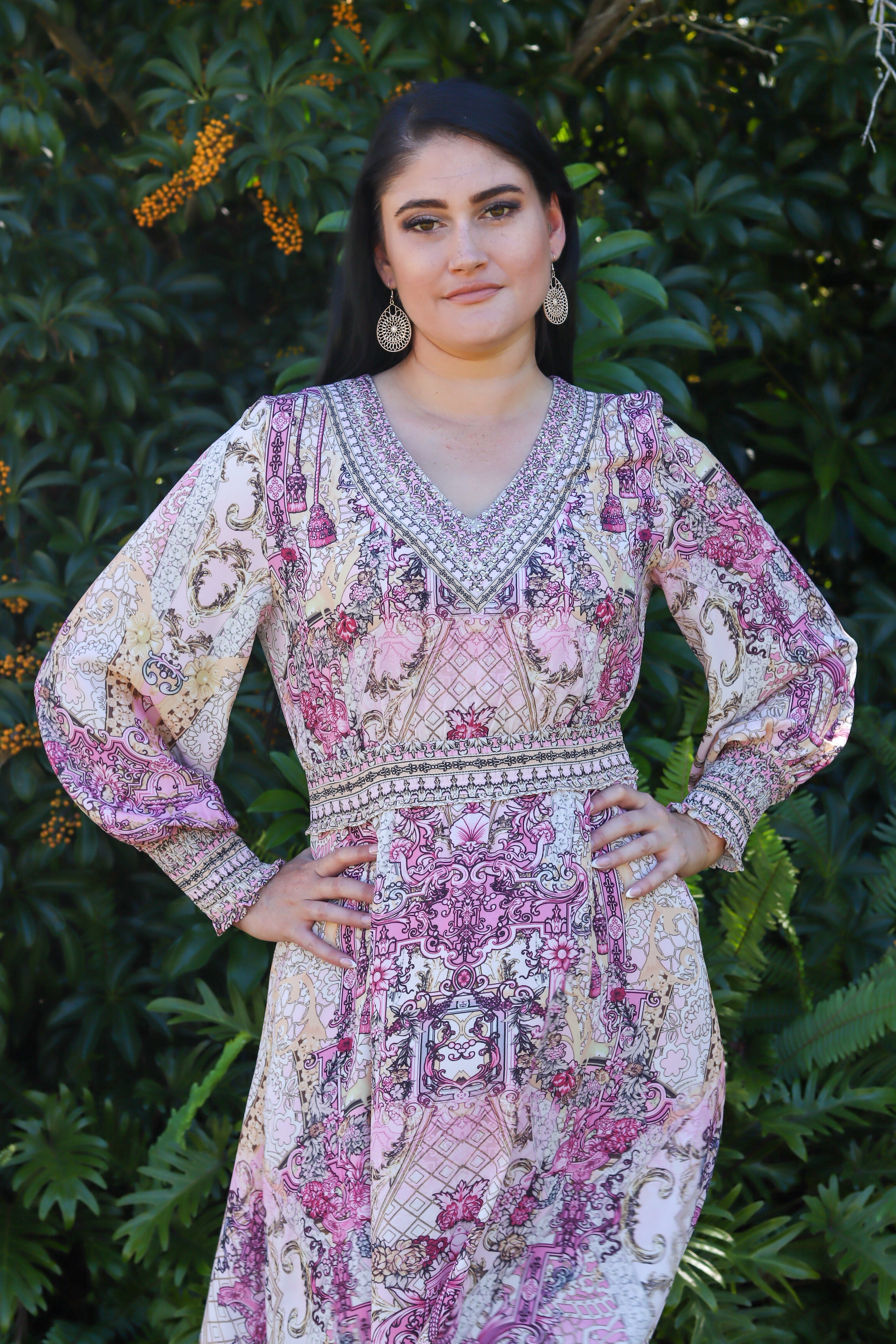 Woman wearing a patterned dress standing in front of green foliage