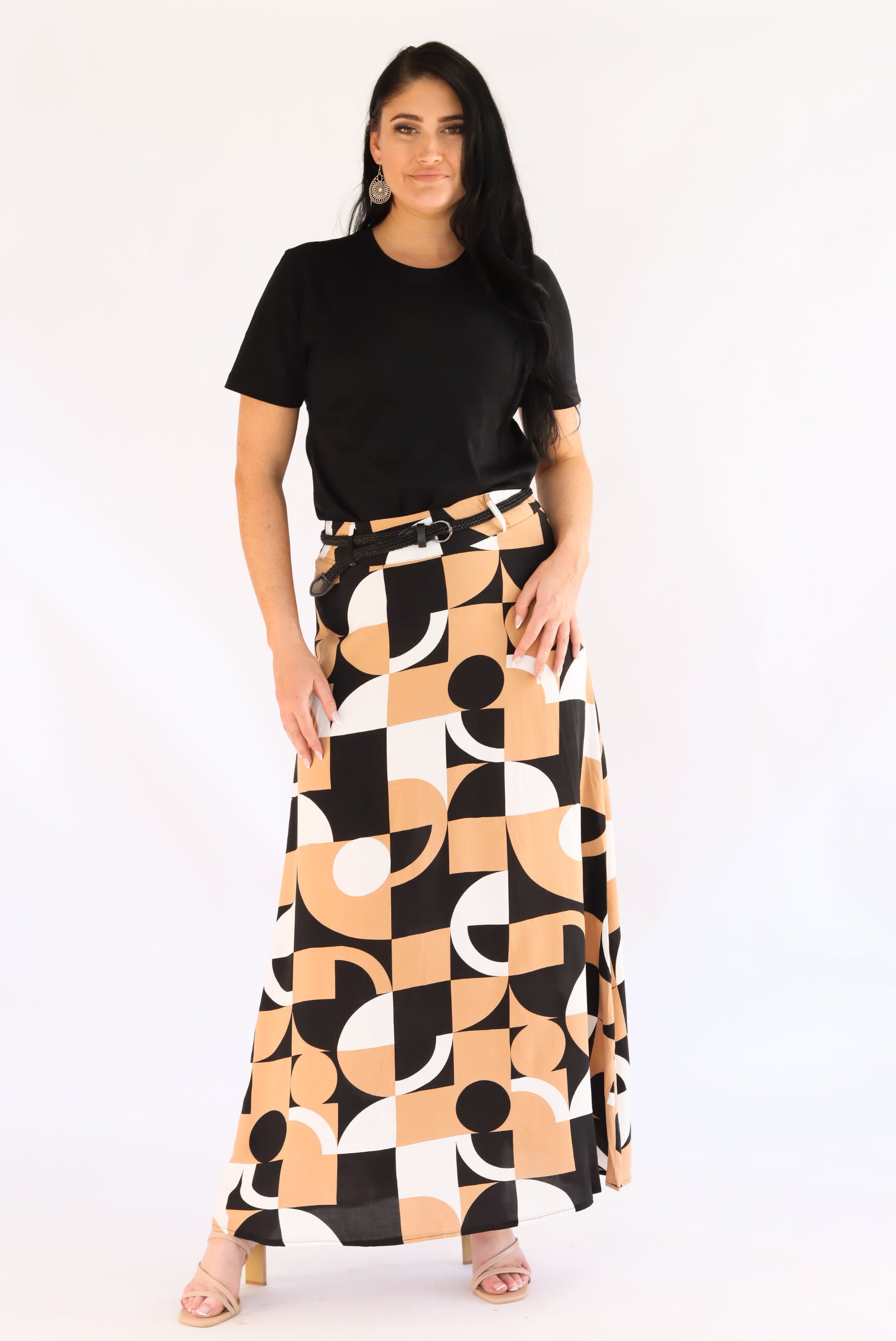 Woman wearing a black top and a long, patterned skirt on a white background