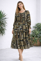 Woman wearing a patterned dress standing in a room with plants.