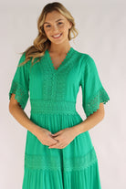 Woman wearing a green dress with lace details on a white background