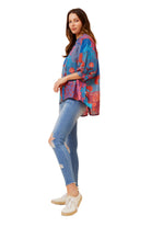 Woman wearing a colorful patterned top and blue jeans 