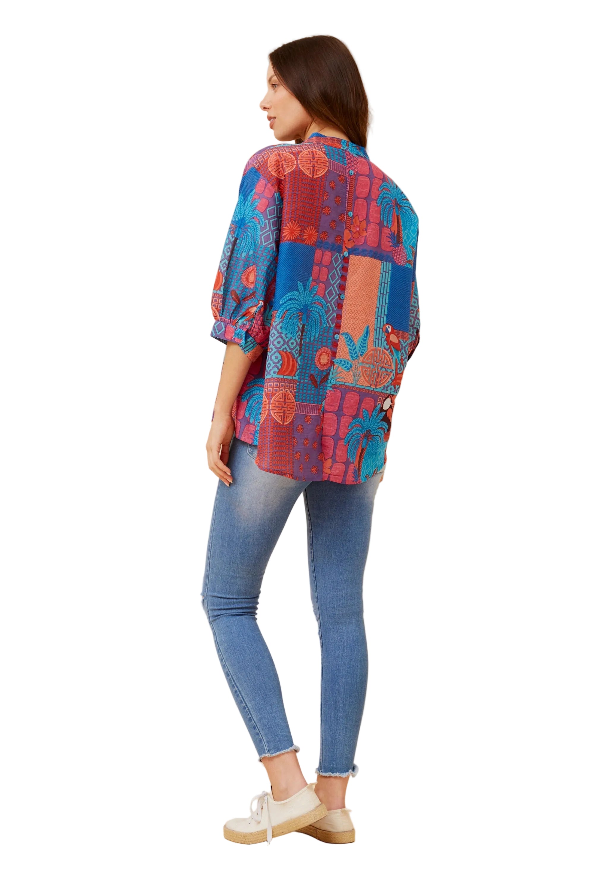 Woman wearing a colorful patterned shirt showing backside of top