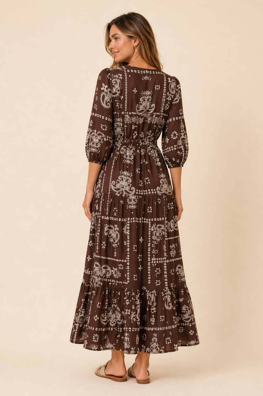 Woman wearing a brown patterned dress on a beige background