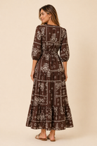 Woman wearing a brown patterned dress on a beige background