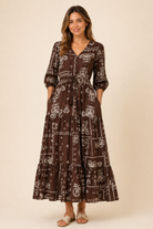 Woman wearing a brown patterned dress against a beige background