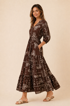 Woman wearing a brown patterned dress on a beige background
