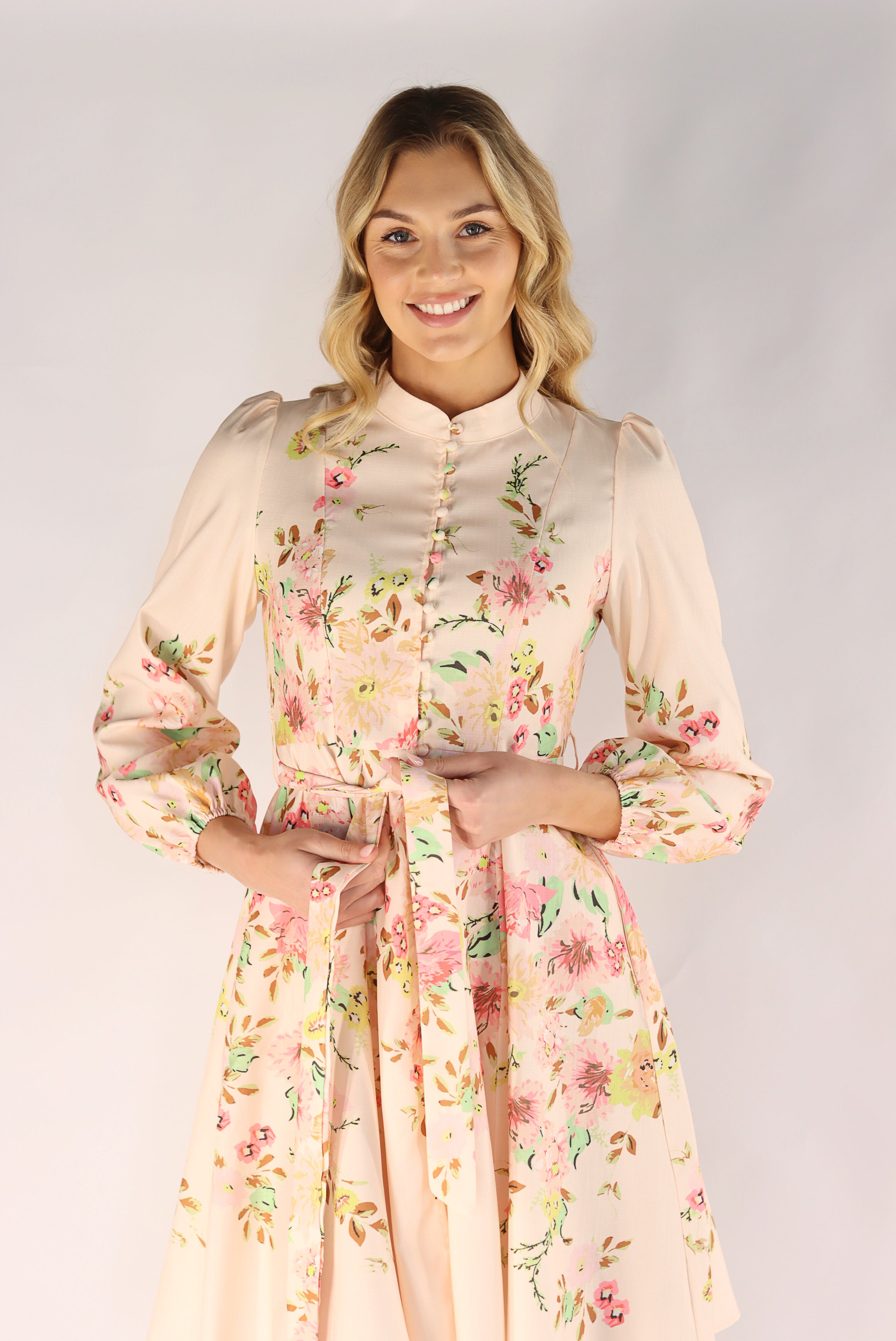 Woman wearing a floral dress against a plain background