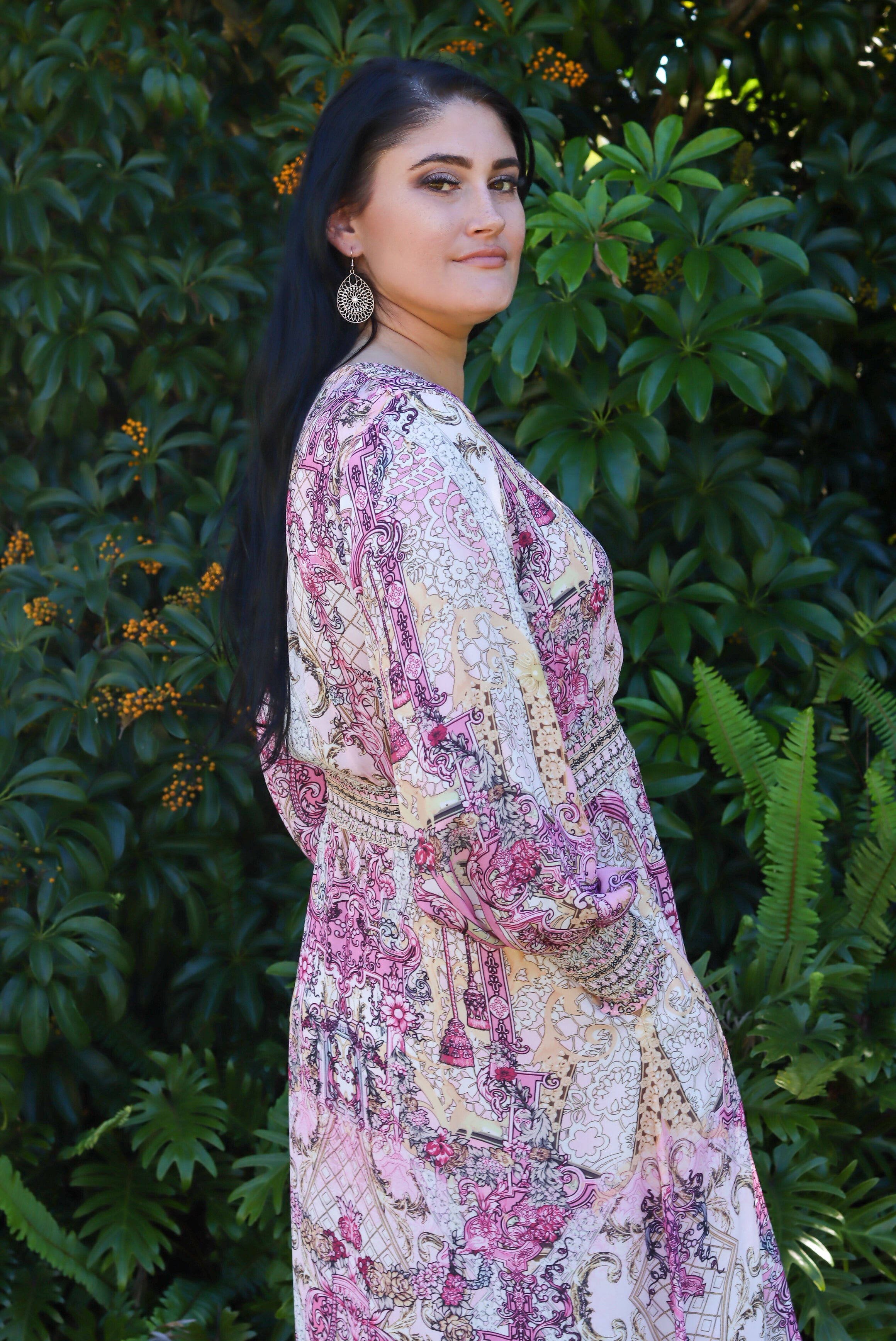 Woman wearing a floral dress standing in front of green foliage