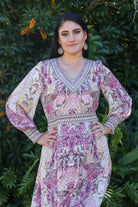 Woman wearing a patterned dress standing in front of green foliage